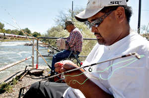 (Andy Sawyer photo) Alan Tahsequah, right, rigs a pole while fishing for salmon with Richard Compo below Parker Dam on the Yakima River Wednesday, June 13, 2012.