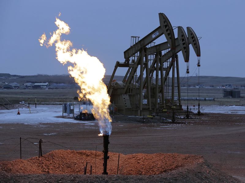 Oil pump jacks work behind a natural gas flare near Watford City, N.D., in 2014. The oil and gas industry is lobbying lawmakers to repeal a rule that aims to limit the emissions of methane, the chief component of natural gas.