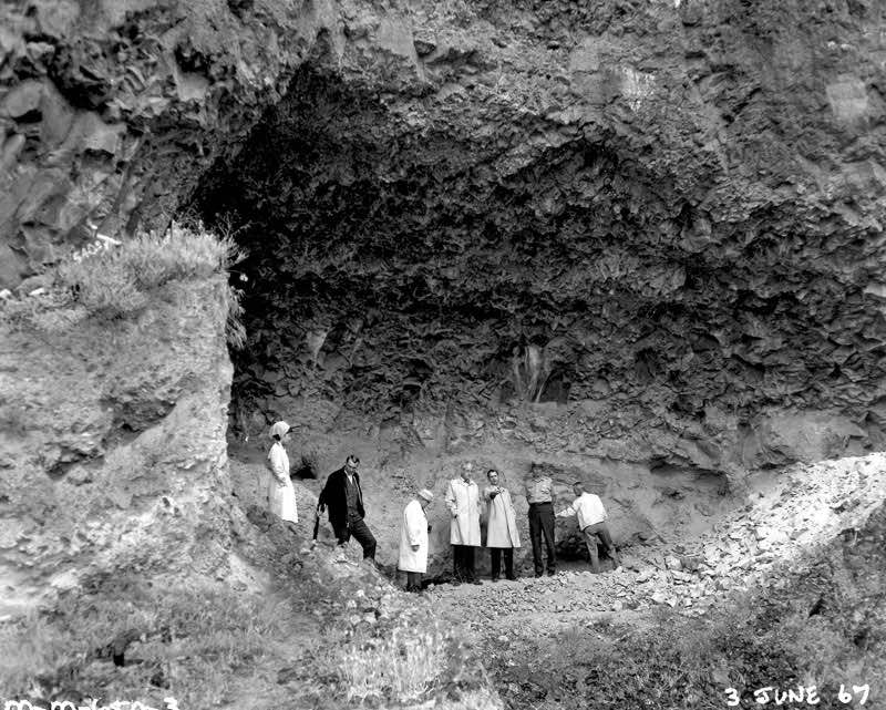 Unknown officials at the Marmes Rock Shelter in Franklin County, Washington. In 1969, the site was submerged in water when a levee protecting it from waters rising behind the then newly constructed Lower Monumental Dam, which was 20 miles (32 km) down the Snake River, failed to hold back water that leaked into the protected area through gravel under the soil,[4] creating Lake Herbert G. West. (ACOE photo)