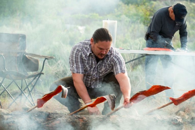 Richard Whitney, a wildlife manager at Colville Tribes Fish and Wildlife, prepares salmon immediately after an early morning salmon ceremony. The salmon is skewered and then placed over a fire, to be eaten for lunch just a few hours later. (photo: Chona Kassinger for ProPublica / OPB).