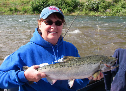 Evelyn Kaide, who's run The Guide Shop in Orofino, Idaho, for 20 years, takes time to land a spring chinook salmon on the Clearwater River