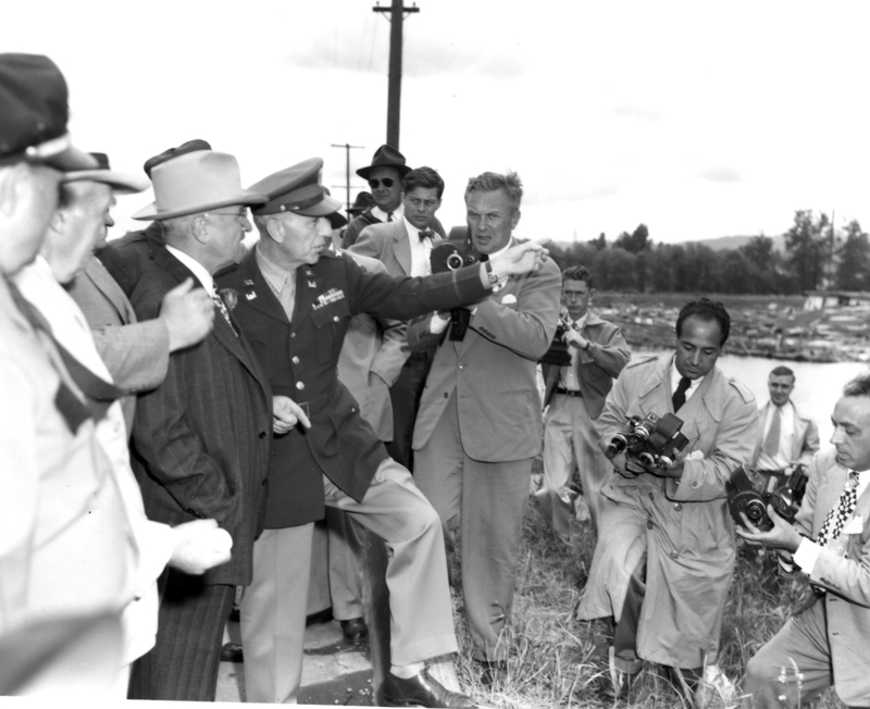 President Harry S. Truman, surrounded by reporters, stands on the bank of the Columbia River while an unidentified officer points out the flood disaster at Vanport, Oregon (date: June 11, 1948). The photos were taken during President Truman's trip to the West Coast. (Naval Photo Center)