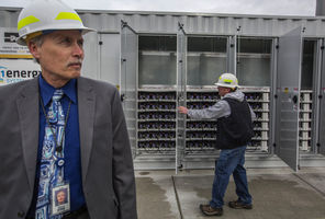 (Steve Ringman photo) Snohomish PUD Chief Executive Steve Klein says the huge lithium-ion battery system behind him can store enough energy to power 400 families for an hour. PUD foreman Scott Westphal opens doors to the inner workings, housed in a former shipping container.