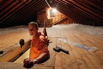 Stephen Botelho stands in the entrance to his attic, at his Westwood, Mass., home. Botelho has installed cellulose insulation to the attic as an energy saving measure. (Steven Senne/AP Photo)