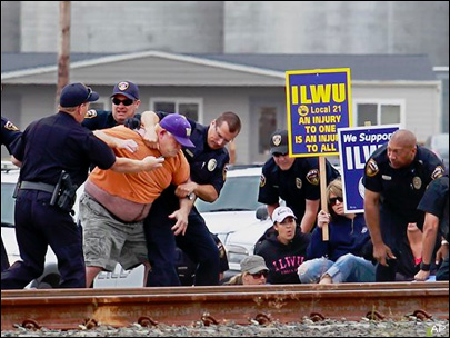 (Bill Wagner) Law enforcement personnel wrestle ILWU Local 21 longshoreman Kelly Muller to the ground as they arrest protesters and try to clear the tracks at the Port of Longview Wednesday.