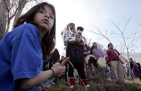 Jaelin Eaglespeaker, 7, left, watches for the arrival of the Puyallup tribal canoe Saturday near the Columbia River site where waters from The Dalles Dam submerged Celilo Falls 50 years ago. Celilo Chief Olsen Meanus Jr., center, waited in eagle-feather regalia to welcome visitors ashore.