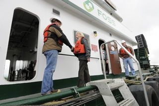 (Troy Wayrynen) U.S. Sen. Patty Murray shakes hands with deckhand Robert Vollmer, left, as she boards the P.J. Brix tugboat . In the background is David Lee, right, also a deckhand on the P.J. Brix.