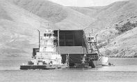 (Kyle Mills) Two Tidewater tug boats maneuver the 1,000-ton prototype removable spillway weir near Lower Granite Dam.  The $11 million device will be attached to one of the spillways to aid migrating salmon.  It was parked above the dam Monday afternoon.