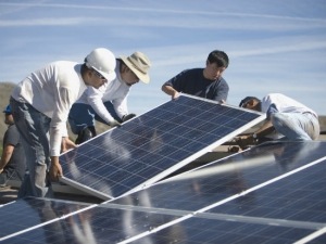 Many hands helping out to install solar. Solar co-ops bring affordable green power to the people.