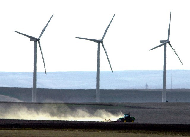 Wind turbines tower over a tractor and plow tilling farmland near Wasco, Ore., March 4, 2002. (Don Ryan AP photo)